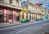 Young men of Cuba leaning against their Classic Green automobile in Havana Centro Cuba