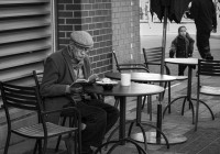 Old man reading a book at sidewalk cafe in Vancouver