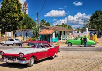 Two-Classic-cars-stopped-at-a-stand-for-Jugo-De-Cana-in-Iznaga-Cuba