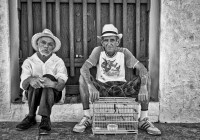 Two Elderly Cubans stting on doorstep with birdcage in Trinidad Cuba